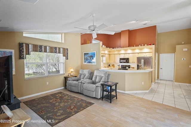 tiled living room with ceiling fan and high vaulted ceiling