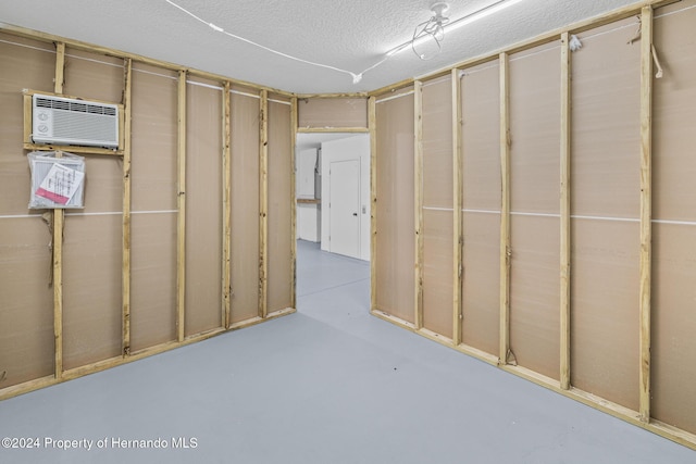 basement featuring a wall mounted air conditioner and a textured ceiling