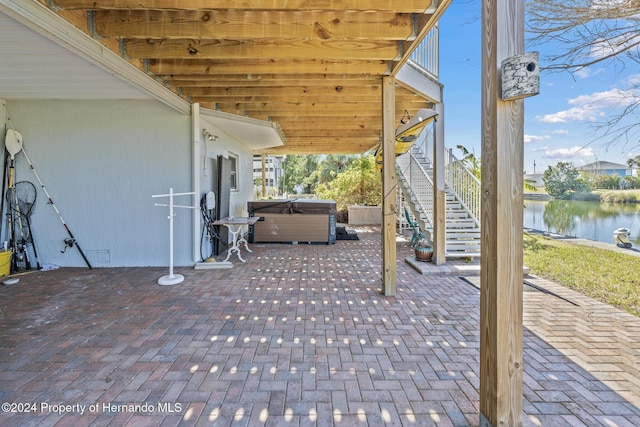 view of patio / terrace featuring a water view and a hot tub