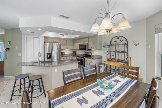 dining area with light tile patterned floors, ceiling fan with notable chandelier, and sink