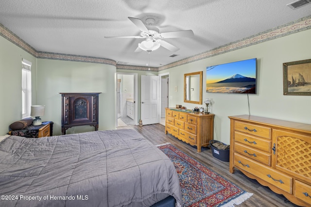 bedroom with ensuite bathroom, ceiling fan, dark wood-type flooring, and a textured ceiling