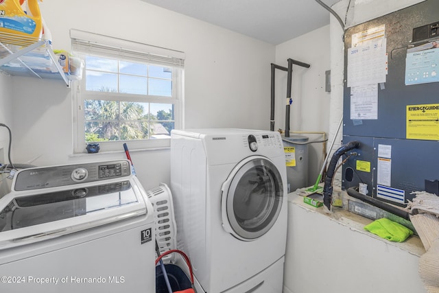 laundry area with washing machine and clothes dryer, heating unit, and water heater