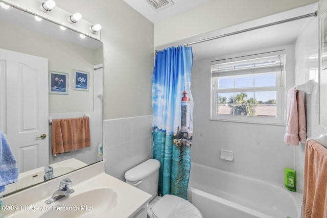 full bathroom featuring shower / tub combo, vanity, toilet, and tile walls