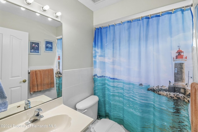 bathroom featuring a shower with curtain, vanity, tile walls, and toilet