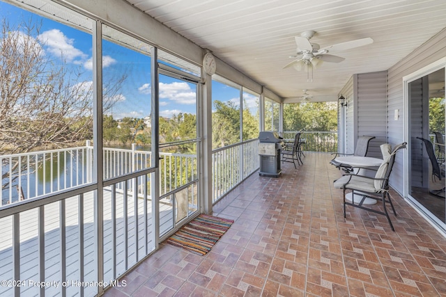 unfurnished sunroom featuring a water view and ceiling fan