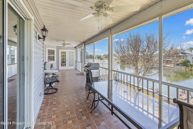 sunroom / solarium featuring a water view and ceiling fan