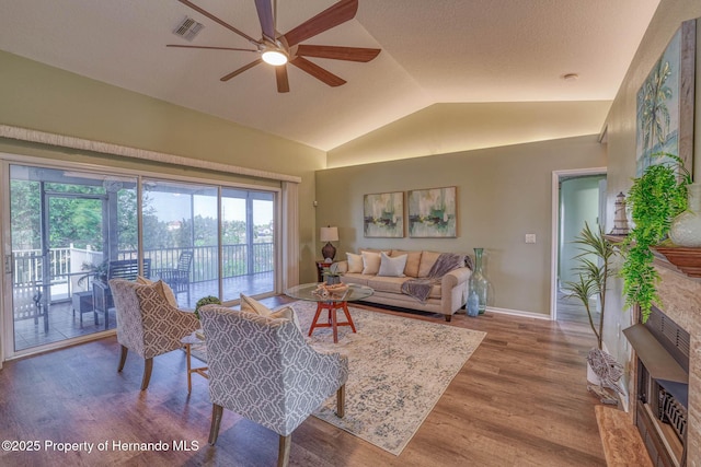 living area featuring visible vents, baseboards, ceiling fan, wood finished floors, and lofted ceiling