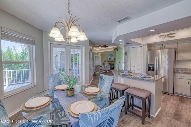dining room with visible vents, baseboards, light wood-type flooring, and ceiling fan with notable chandelier