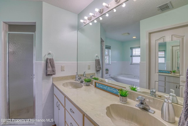 full bathroom with a sink, visible vents, a shower stall, and a garden tub