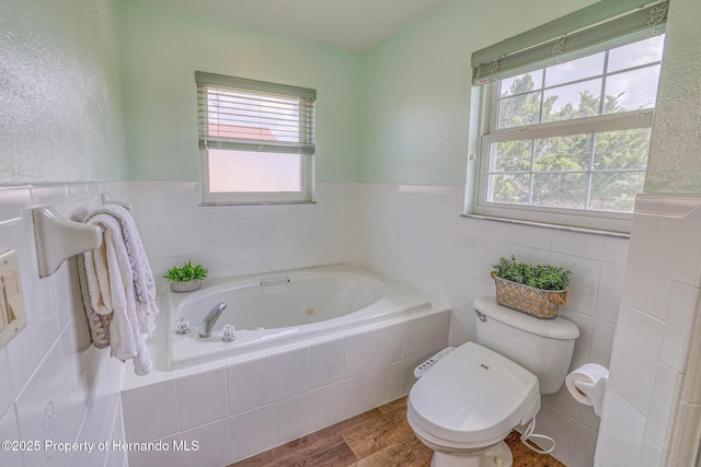 bathroom featuring a wealth of natural light, a jetted tub, toilet, and wood finished floors