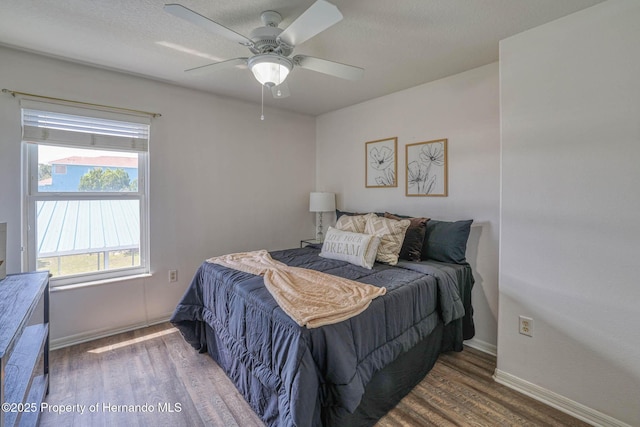 bedroom featuring wood finished floors, baseboards, and a ceiling fan