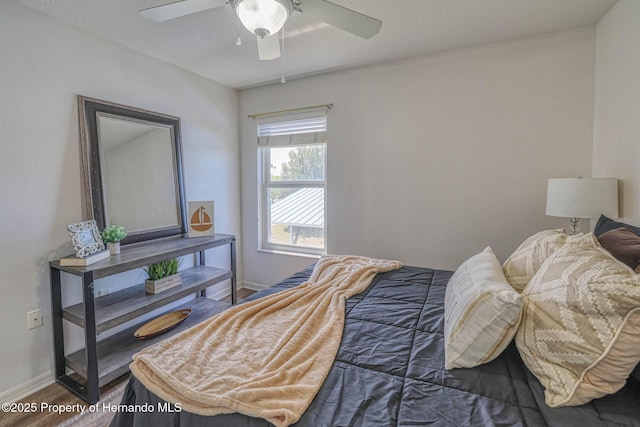 bedroom featuring wood finished floors, baseboards, and a ceiling fan