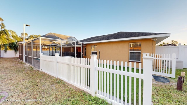 exterior space featuring a lawn and a lanai