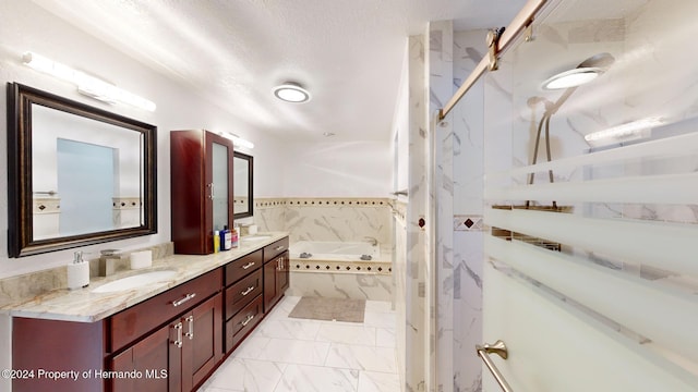 bathroom featuring vanity, a relaxing tiled tub, and a textured ceiling