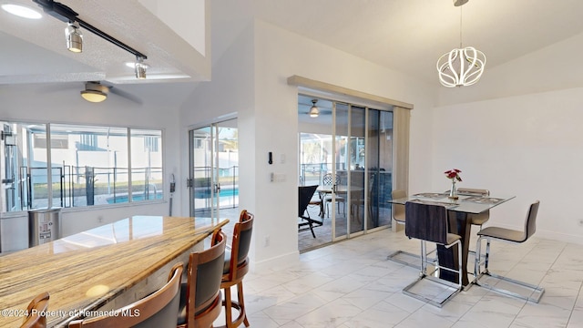 dining space with ceiling fan with notable chandelier, a healthy amount of sunlight, lofted ceiling, and a textured ceiling