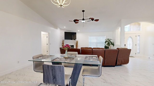 dining area with a large fireplace, high vaulted ceiling, and ceiling fan