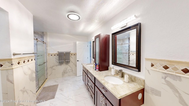 bathroom with vanity, tile walls, and walk in shower