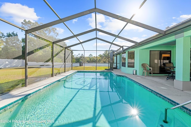 view of swimming pool featuring a lanai, a yard, and a patio