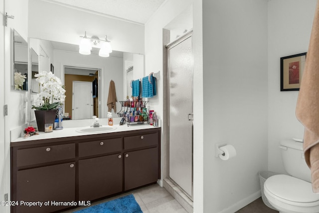 bathroom with a shower with door, vanity, tile patterned flooring, and toilet