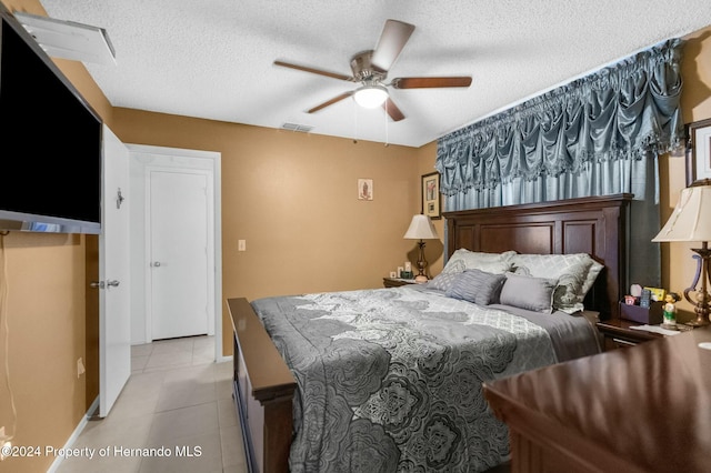 bedroom featuring ceiling fan, light tile patterned floors, and a textured ceiling