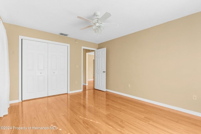 unfurnished bedroom featuring hardwood / wood-style floors, ceiling fan, and a closet