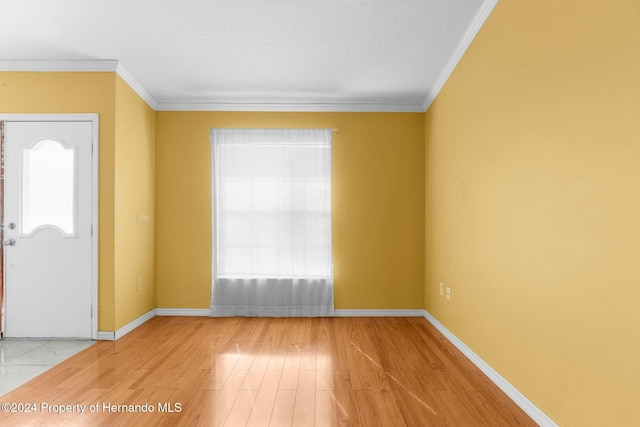 entryway featuring light wood-type flooring, a wealth of natural light, and ornamental molding