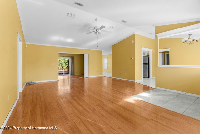 spare room with crown molding, ceiling fan with notable chandelier, vaulted ceiling, and light wood-type flooring