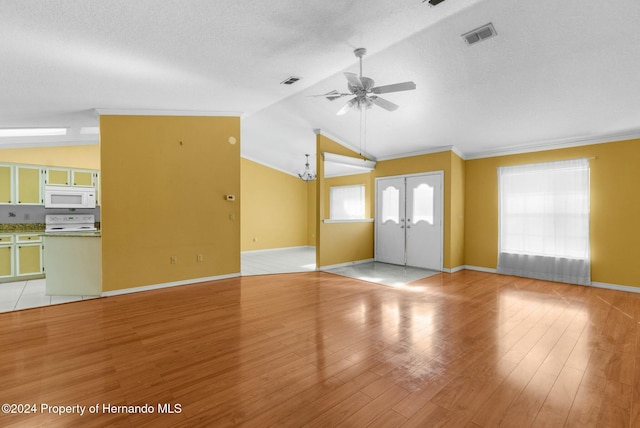 unfurnished living room featuring light hardwood / wood-style floors, ornamental molding, a textured ceiling, and vaulted ceiling