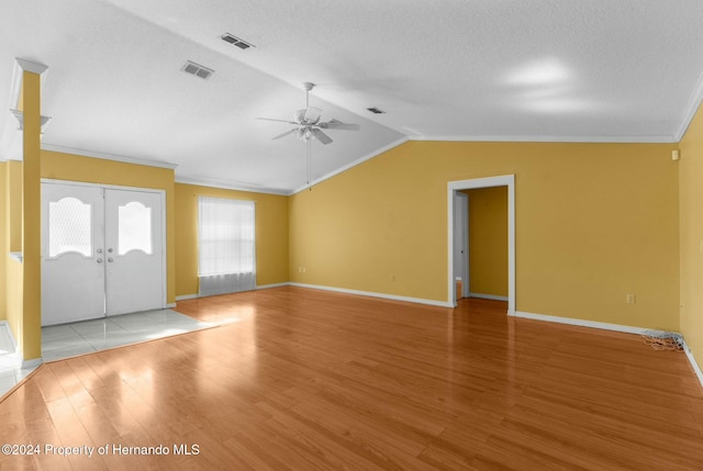 unfurnished living room featuring french doors, light hardwood / wood-style flooring, lofted ceiling, and crown molding