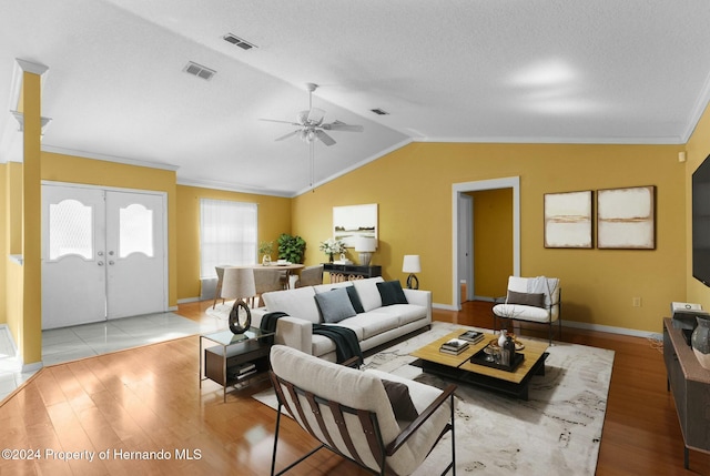 living room featuring light hardwood / wood-style floors, lofted ceiling, ornamental molding, and french doors