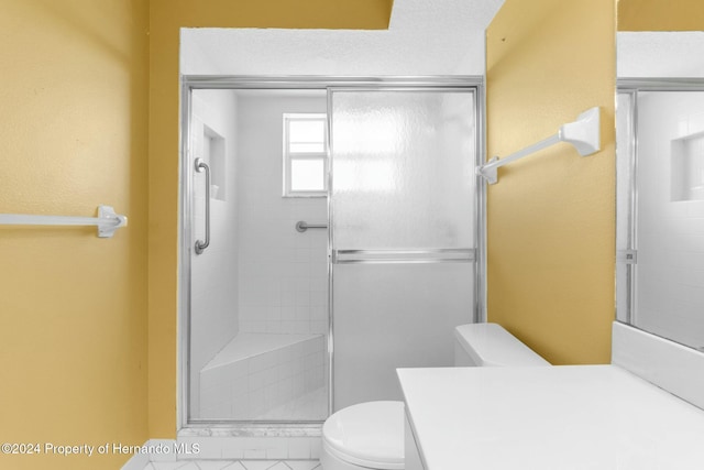 bathroom with a shower with door, vanity, and toilet