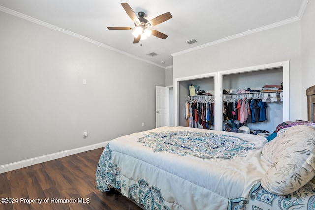 bedroom featuring dark hardwood / wood-style floors, ceiling fan, ornamental molding, and two closets