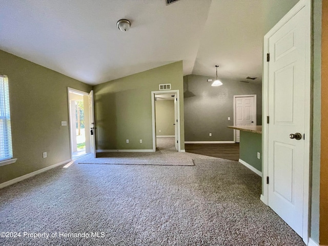 unfurnished living room with dark carpet and vaulted ceiling