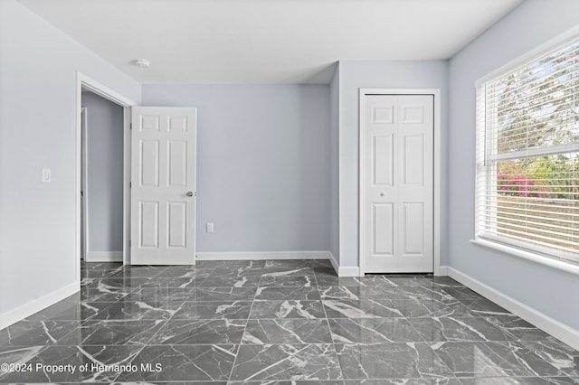 unfurnished bedroom featuring multiple windows and a closet