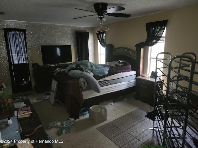 bedroom featuring carpet, ceiling fan, a textured ceiling, and multiple windows