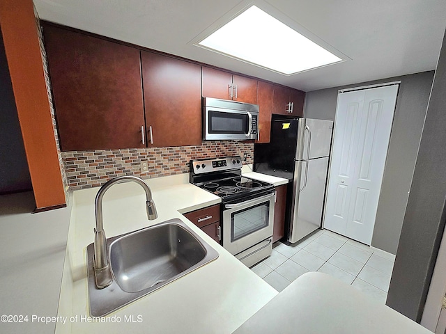 kitchen featuring decorative backsplash, light tile patterned floors, sink, and appliances with stainless steel finishes