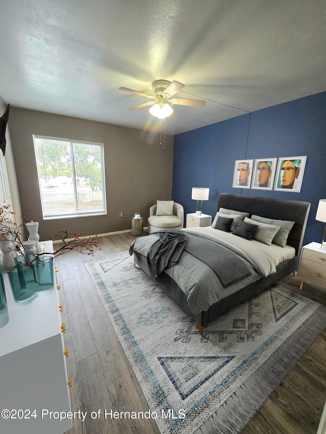 bedroom with ceiling fan, dark hardwood / wood-style floors, and a textured ceiling