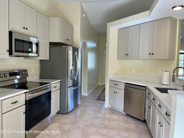 kitchen with white cabinetry, sink, light tile patterned floors, and stainless steel appliances