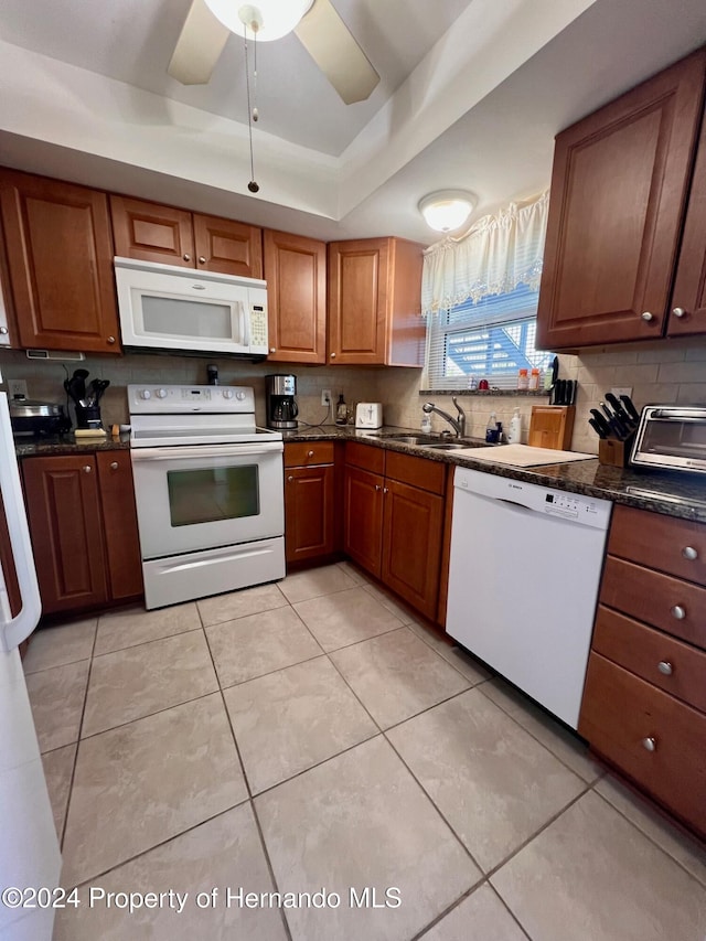 kitchen with white appliances, ceiling fan, sink, light tile patterned floors, and dark stone countertops