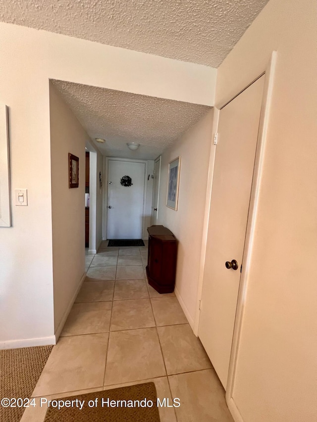 hallway featuring light tile patterned flooring and a textured ceiling