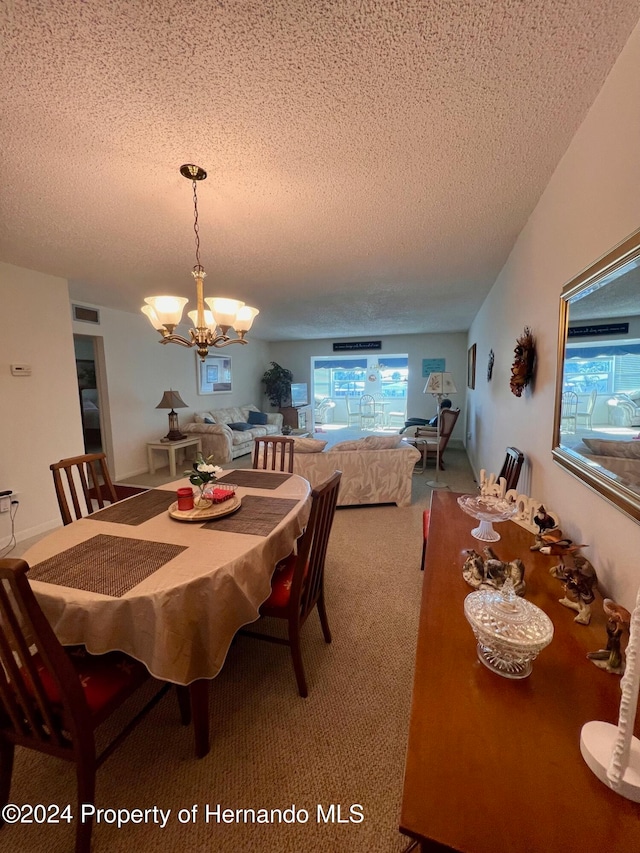 dining room featuring carpet floors, a chandelier, and a textured ceiling