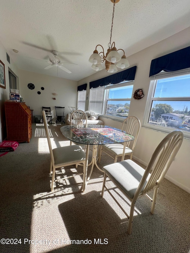 dining room featuring carpet flooring, a textured ceiling, and ceiling fan with notable chandelier