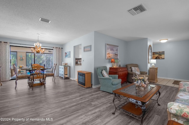 living room featuring a textured ceiling, a notable chandelier, and hardwood / wood-style flooring