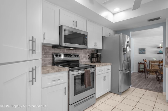 kitchen with decorative backsplash, light tile patterned floors, stainless steel appliances, and white cabinetry