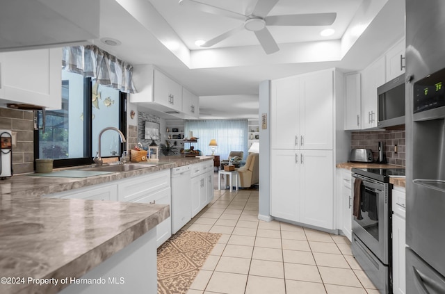 kitchen featuring a tray ceiling, white cabinets, and appliances with stainless steel finishes