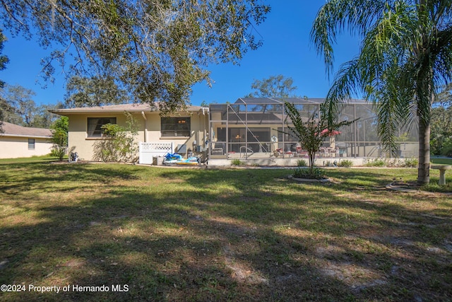 back of house with a lanai and a lawn