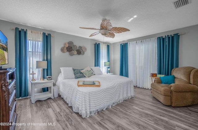 bedroom featuring ceiling fan, wood-type flooring, and a textured ceiling