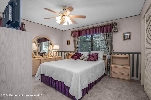 carpeted bedroom with ceiling fan, a textured ceiling, and multiple windows