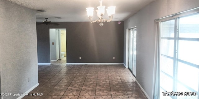 empty room featuring ceiling fan with notable chandelier