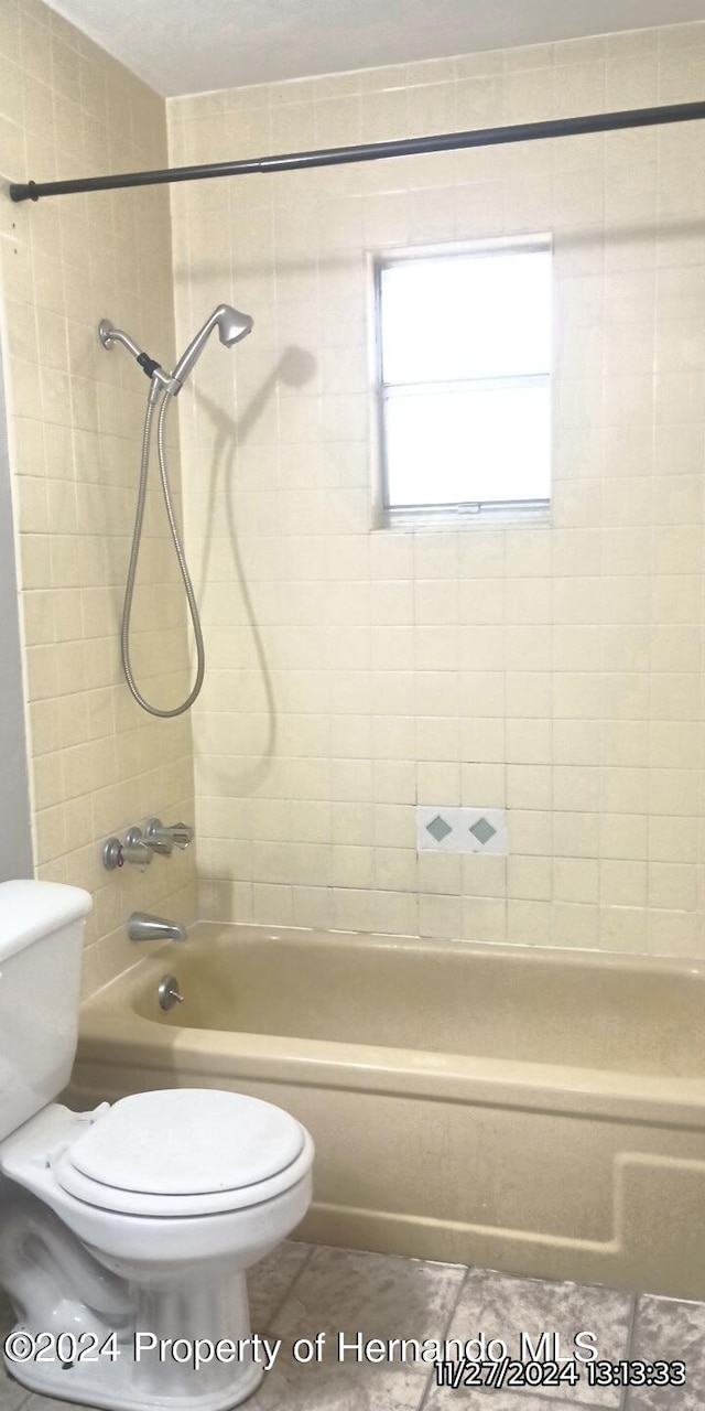 bathroom featuring tile patterned floors, tiled shower / bath, and toilet